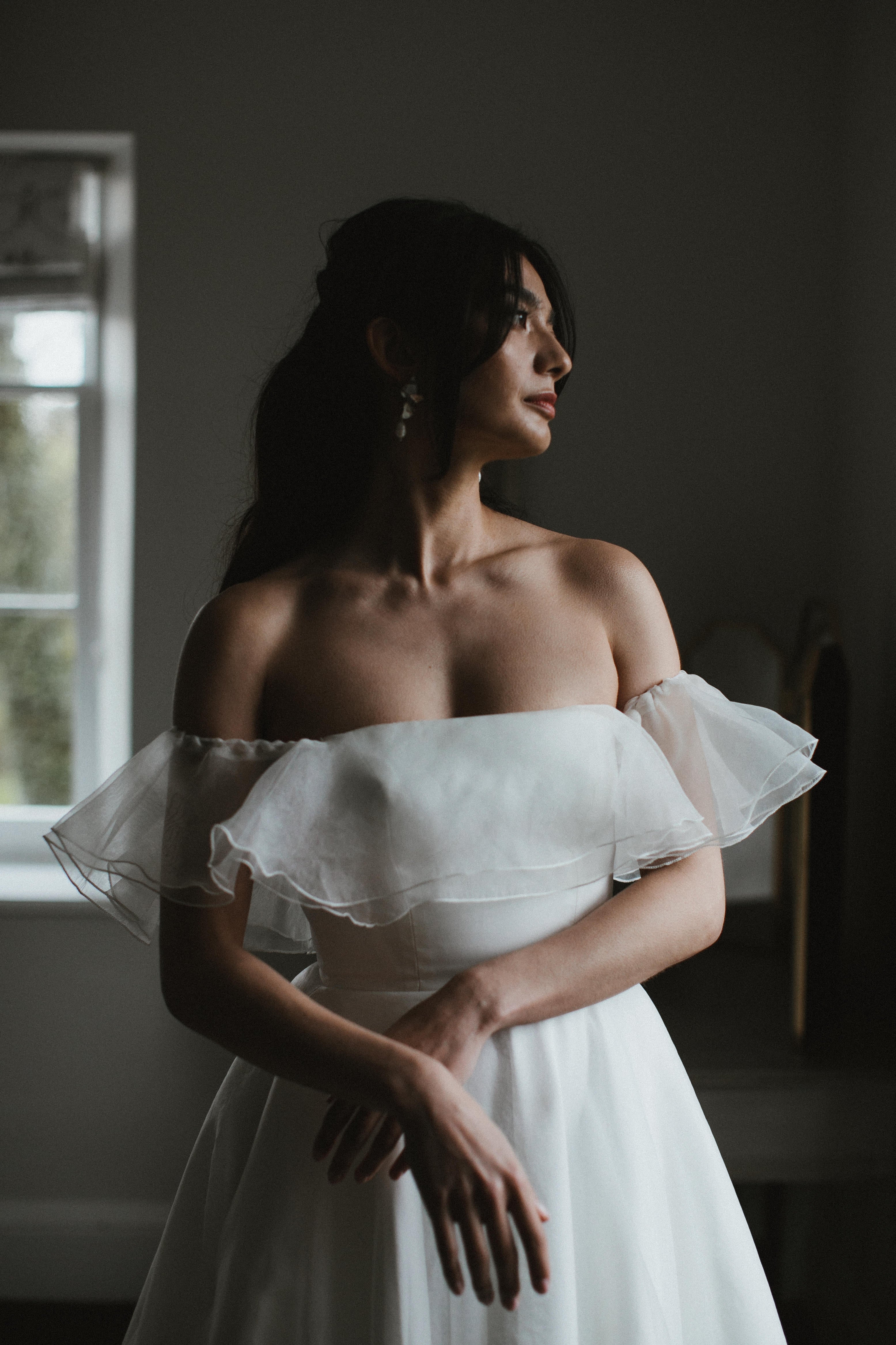 Model wearing our Monroe wedding dress, a structured, corseted organza dress with frill, bardot neckline and pockets.