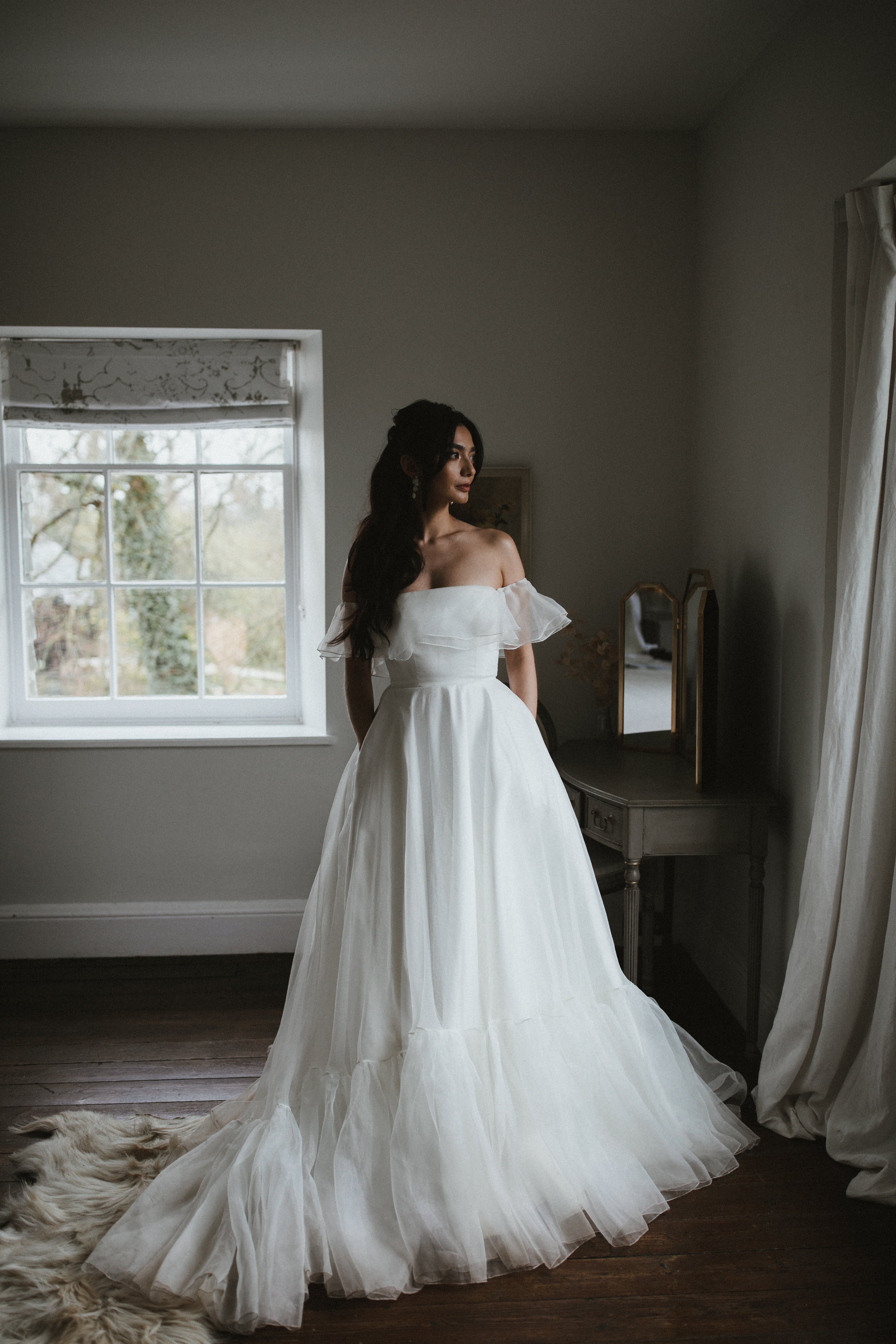Model wearing our Monroe wedding dress, a structured, corseted organza dress with frill, bardot neckline and pockets.