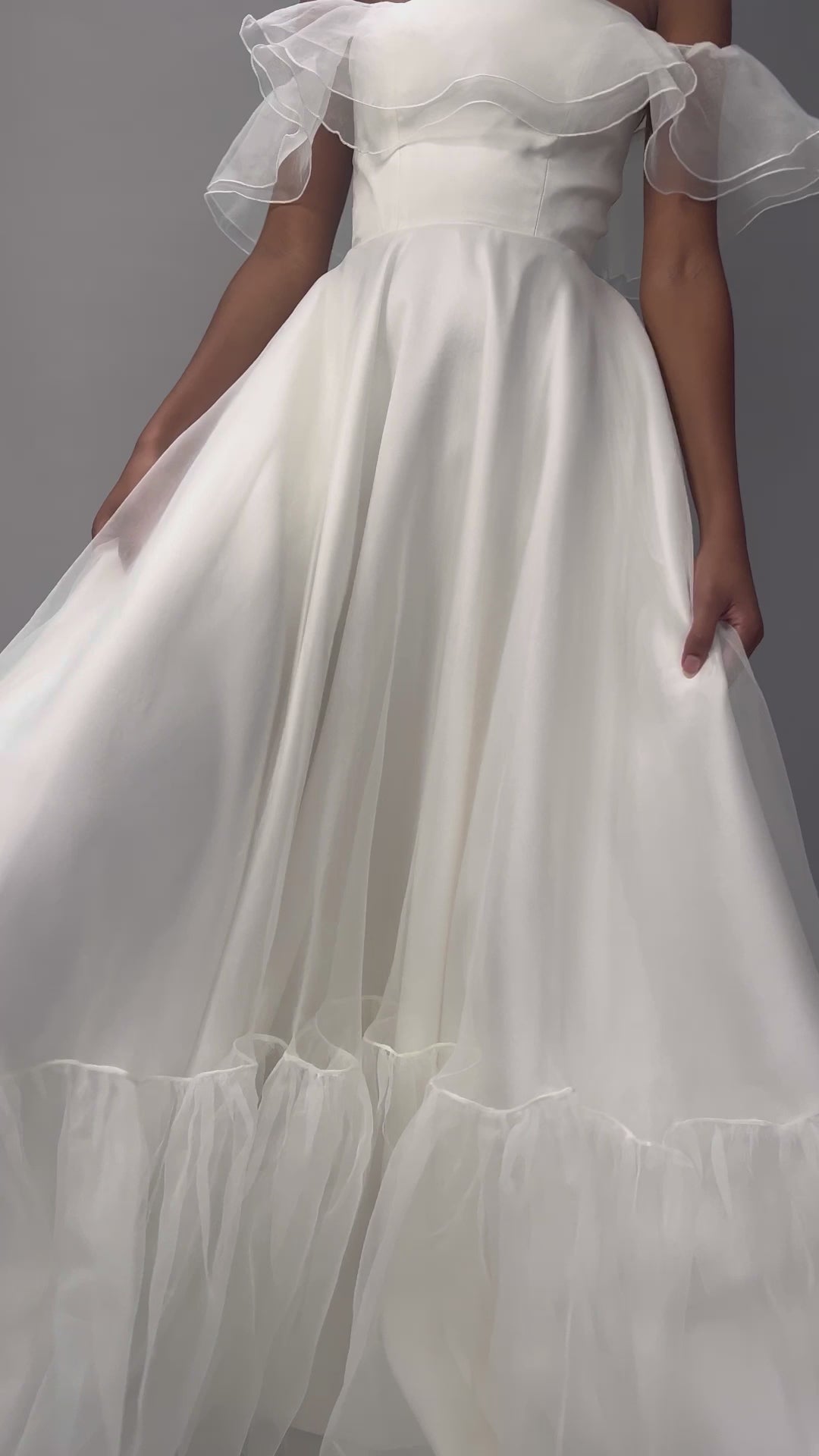 Model wearing our Monroe wedding dress, a structured, corseted organza dress with frill, bardot neckline and pockets. A close up video showing details