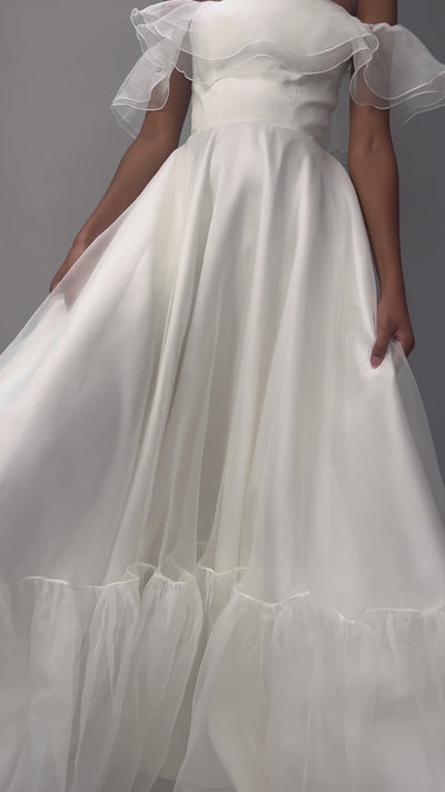 Model wearing our Monroe wedding dress, a structured, corseted organza dress with frill, bardot neckline and pockets. A close up video showing details